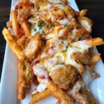 Garlic parmesan fries topped with boneless chicken wings marinara sauce and melted mozzarella cheese Copie
